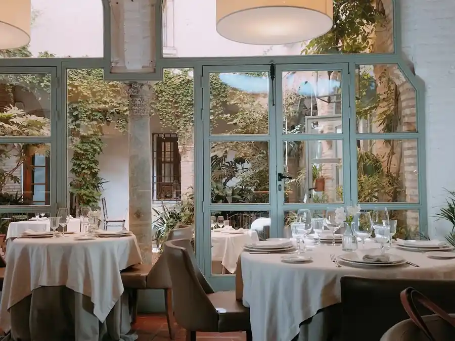 Comedor de La Ermita de la Candelaria abierto a la luz y la vegetación del patio, Córdoba